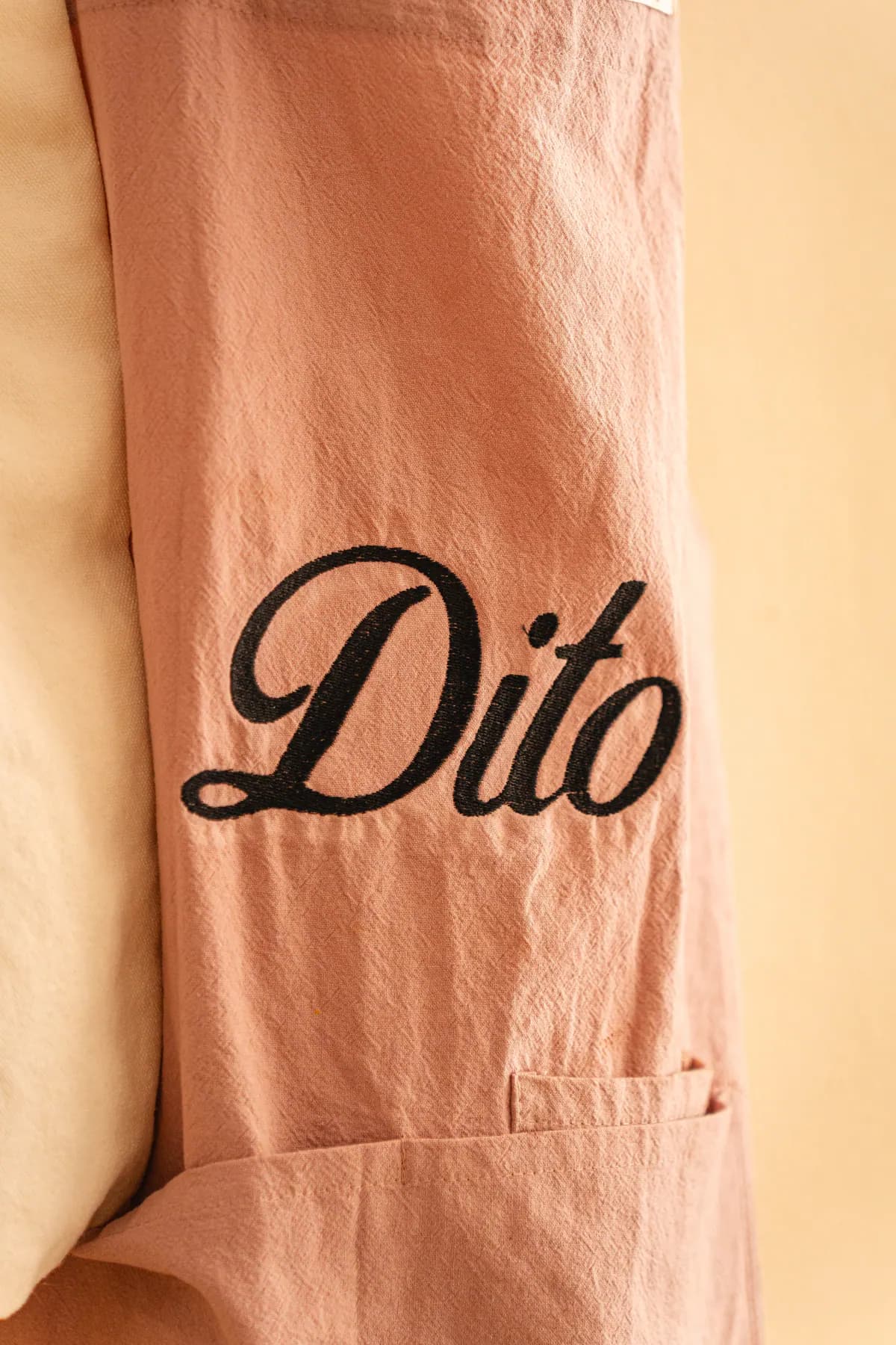 Dito - Brand-Detail: handgenähter 'Dito' Schriftzug in schwarz auf warmem Rosé